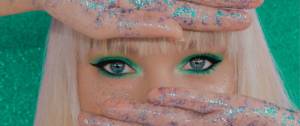 Une femme blonde avec du maquillage vert sur les yeux