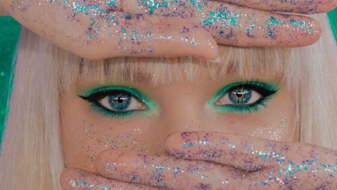 Une femme blonde avec du maquillage vert sur les yeux