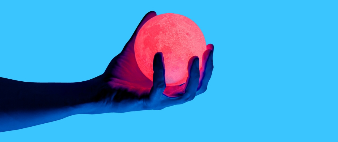 Qu'est-ce que la technologie haptique ? Une main sur fond bleu en train de tenir une boule lumineuse