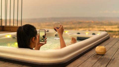 une influenceuse dans un bain qui prend en photo son verre de vin