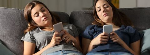 Les jeunes n'agissent pas vraiment pour le climat Deux adolescentes qui regardent leur smartphone allongées sur un canapé