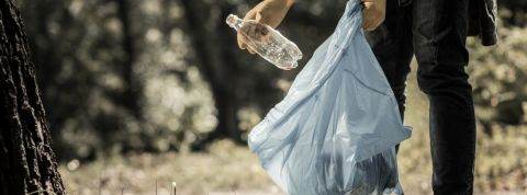 Que prévoit vraiment la loi anti-gaspi ? Un homme en train de jeter une bouteille en plastique dans un sac poubelle