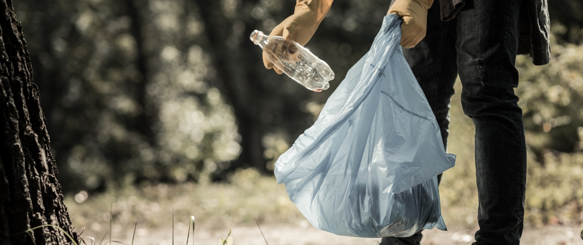 Que prévoit vraiment la loi anti-gaspi ? Un homme en train de jeter une bouteille en plastique dans un sac poubelle