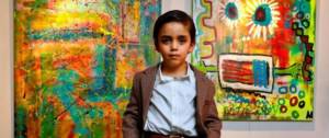 Un enfant artiste pose devant ses peintures