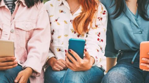 Trois femmes assises tiennent leur téléphone portable