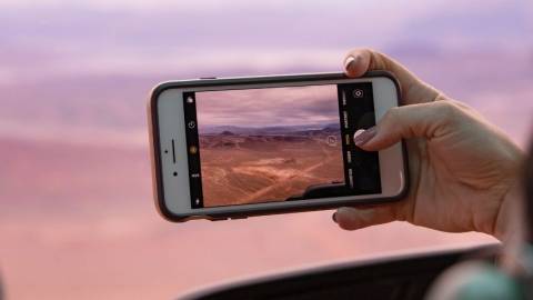 une femme prend une photo d'un paysage rose