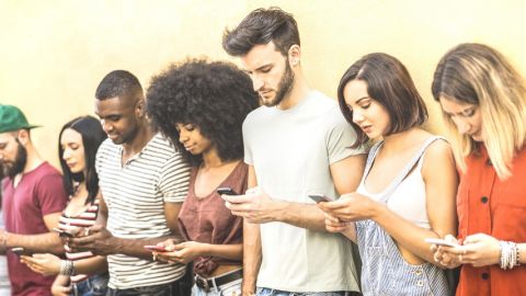 une groupe de jeune gens qui regardent leur portable.