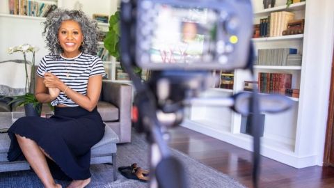 Une femme métisse souriante devant une caméra, influence