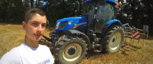 un jeune agriculteur se prend en selfie devant un tracteur