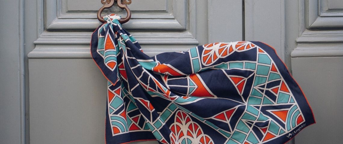 Amédée Paris est la première marque de mode à utiliser la blockchain pour partager en toute transparence les étapes de création de ses produits. Foulard flottant accroché à une porte