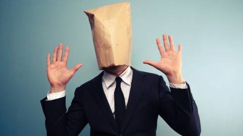 un homme avec un sac en papier sur la tête qui lève les mains