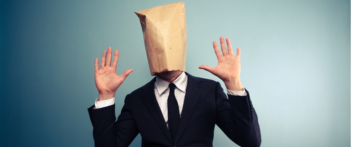 Quel rapport entre l'affaire Griveaux et l'anonymat en ligne ? Aucun un homme avec un sac en papier sur la tête qui lève les mains