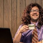 un homme assis à une bureau dans une chemise violette