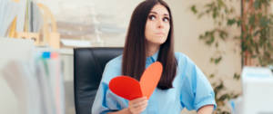 Une femme dans un bureau en train de tenir un coeur rouge en papier