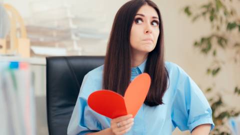 Une femme dans un bureau en train de tenir un coeur rouge en papier