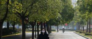 Une femme en Chine avec un masque sur le visage et des arbres autour