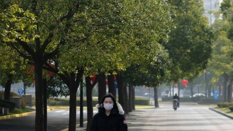 Une femme en Chine avec un masque sur le visage et des arbres autour