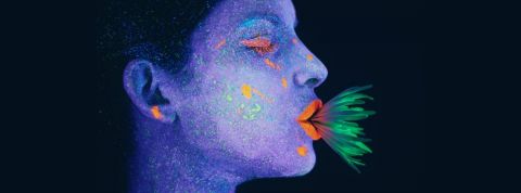 Une femme au visage bleu avec une plante verte dans la bouche