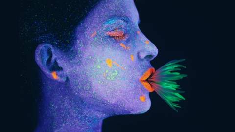 Une femme au visage bleu avec une plante verte dans la bouche