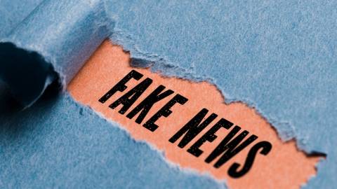 une feuille bleue déchirée qui révèle le mot fake news