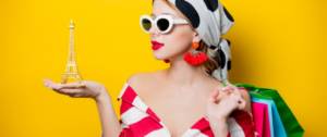 Une femme avec un foulard et des lunettes qui tient un Tour Eiffel dans sa main