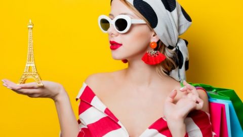 Une femme avec un foulard et des lunettes qui tient un Tour Eiffel dans sa main
