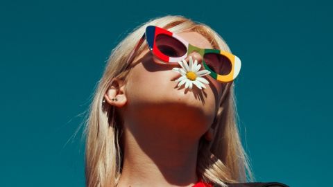 une jeune fille qui à une fleur dans la bouche