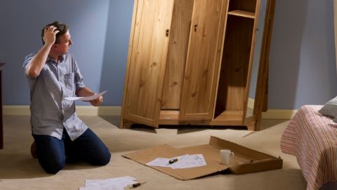 Un homme en train de monter une armoire bancale