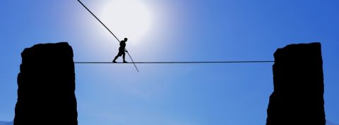 Quel nouveau modèle pour les entreprises ? Un homme en train de marcher sur une corde entre deux falaises