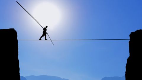 Quel nouveau modèle pour les entreprises ?  Un homme en train de marcher sur une corde entre deux falaises