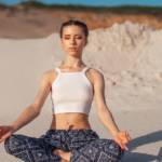 Une femme qui fait du yoga sur la plage