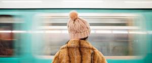 une fille en manteau de fourrure de dos face à un métro