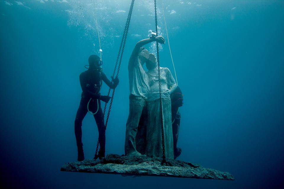 un plongeur immerge une sculpture sous l'eau