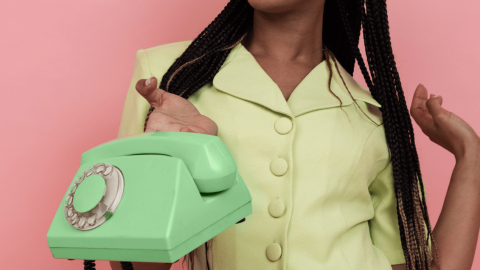 Une femme tenant un téléphone sur fond rose