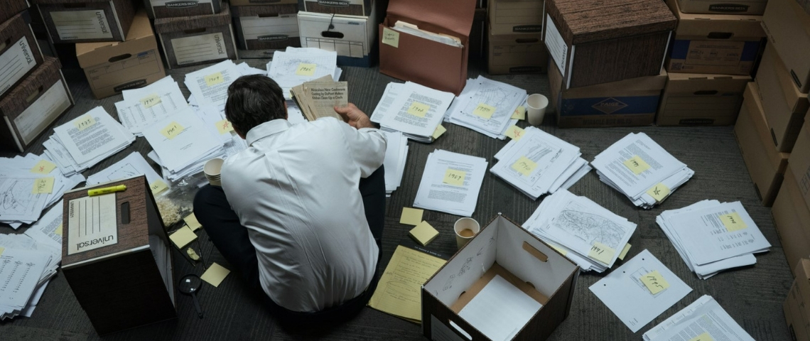 Comment le film Dark Waters révèle le scandale du C8 Mark Ruffalo dans le film Dark Waters, accroupi et de dos en train de travailler sur le dossier DuPont