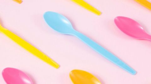 des cuillères en plastique fluo sur fond rose