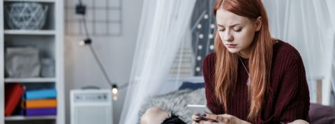 Les ado sont-ils vraiment seuls dans leur chambre ? une adolescente sur son lit regarde son portable