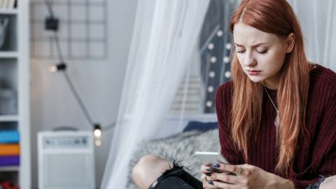 Les ado sont-ils vraiment seuls dans leur chambre ? une adolescente sur son lit regarde son portable