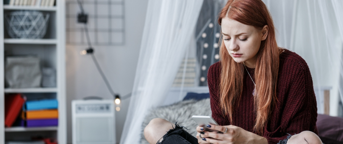 Les ado sont-ils vraiment seuls dans leur chambre ? une adolescente sur son lit regarde son portable