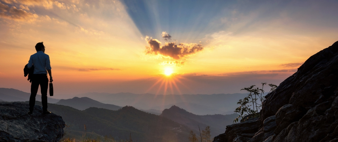 Comment les dirigeants peuvent-ils gérer la crise du coronavirus ? Un homme au sommet d'une montagne en train d'assister au lever du soleil