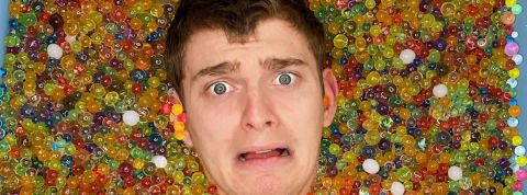 Cyril Schreiner, noyé dans ses billes la tête d'un influenceur qui sort d'une baignoire pleine de billes colorées.