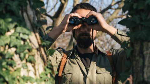 Comment la résistance s'organise face aux fake news ? Un homme dans la jungle avec des jumelles