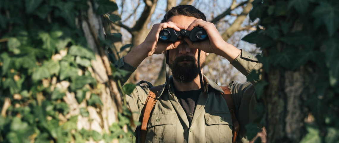 Comment la résistance s'organise face aux fake news ? Un homme dans la jungle avec des jumelles