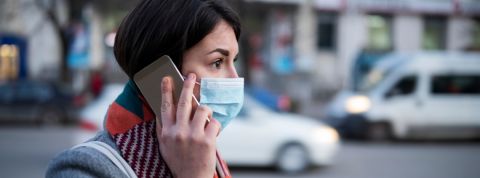 Les gouvernements peuvent utiliser nos données privées pour lutter contre le coronavirus Une femme portant un masque de protection au téléphone