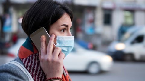 Les gouvernements peuvent utiliser nos données privées pour lutter contre le coronavirus Une femme portant un masque de protection au téléphone
