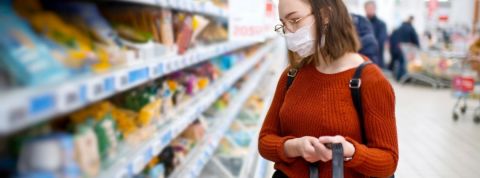 Quel sera l'impact de la crise sur le secteur de la grande distribution ? Une masque qui fait ses courses dans un supermarché avec un masque