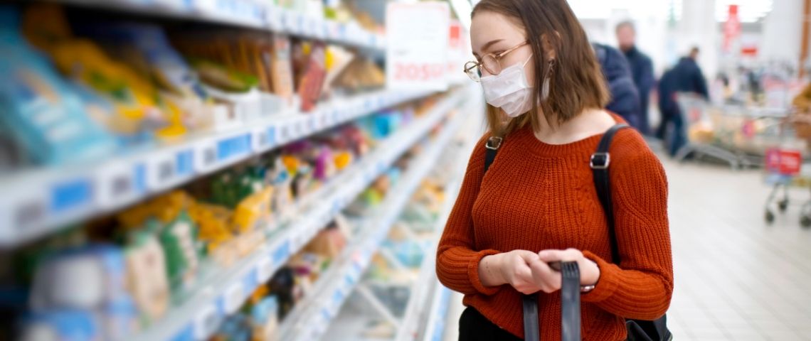 Quel sera l'impact de la crise sur le secteur de la grande distribution ? Une masque qui fait ses courses dans un supermarché avec un masque