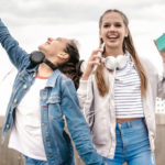 trois adolescentes dansent avec leur portable.