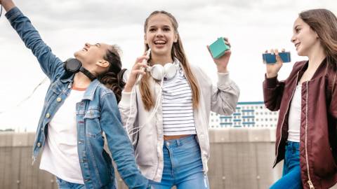 trois adolescentes dansent avec leur portable.