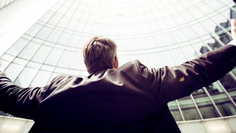 Un homme les bras ouverts devant une tour